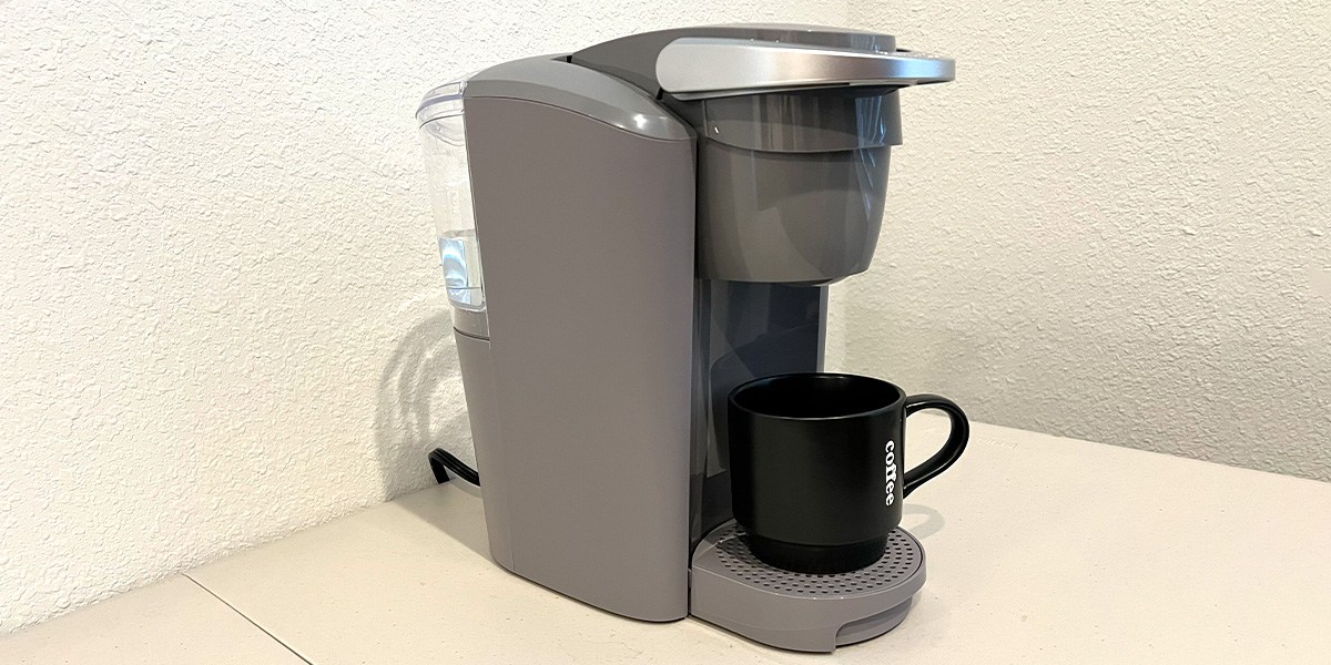 Side view of Keurig K-Compact showing water reservoir and black coffee cup Side view of Keurig K-Compact showing water reservoir and black coffee cup