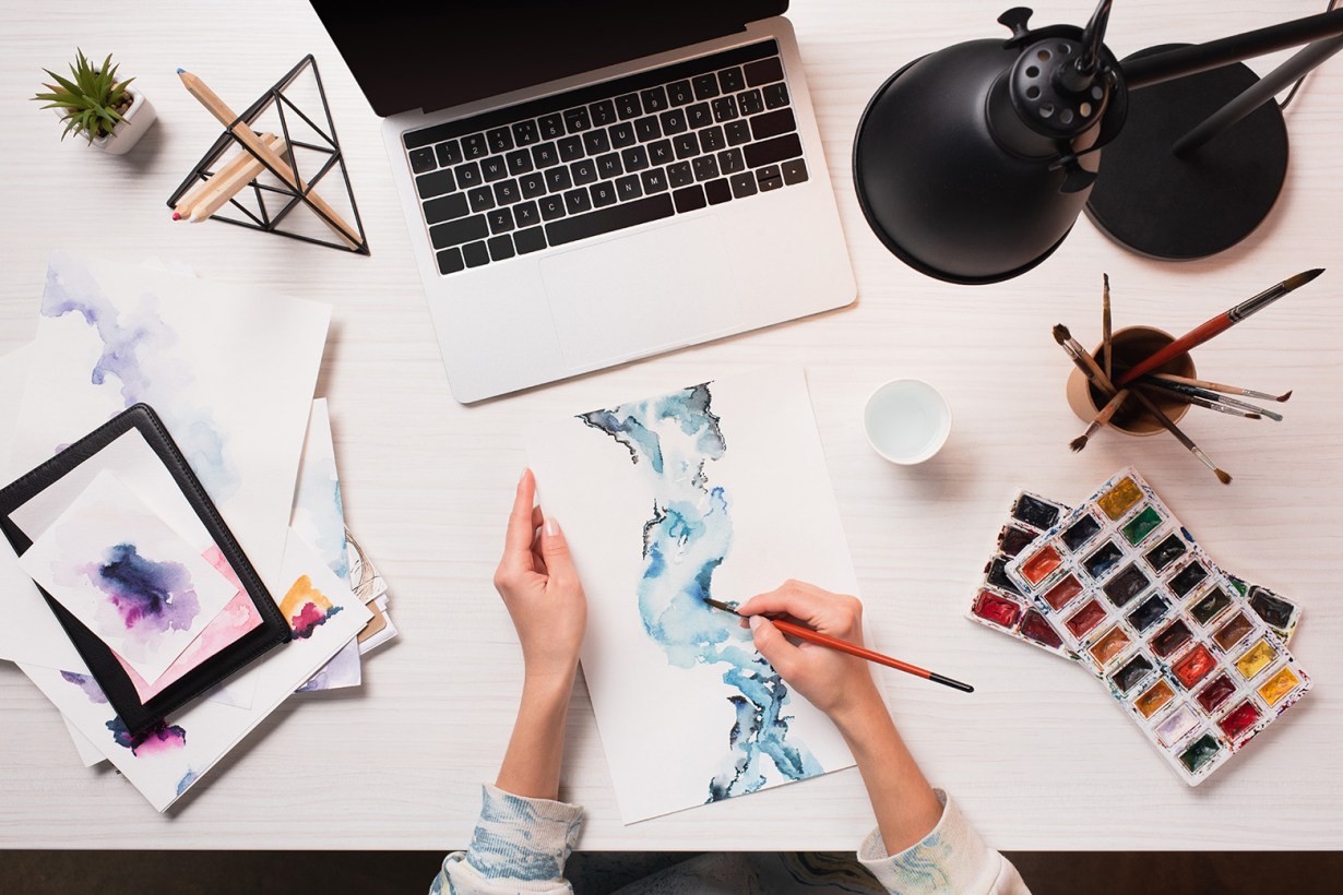 a person using watercolor while in front of a laptop