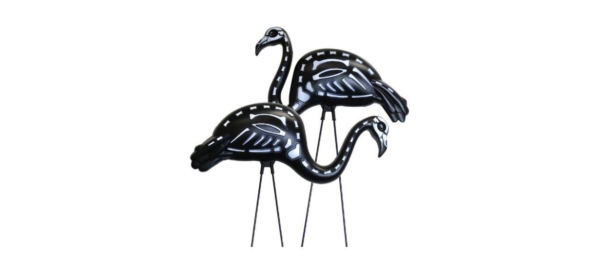 Two black flamingo inflatables on sticks with outlines of their skeletons on them.