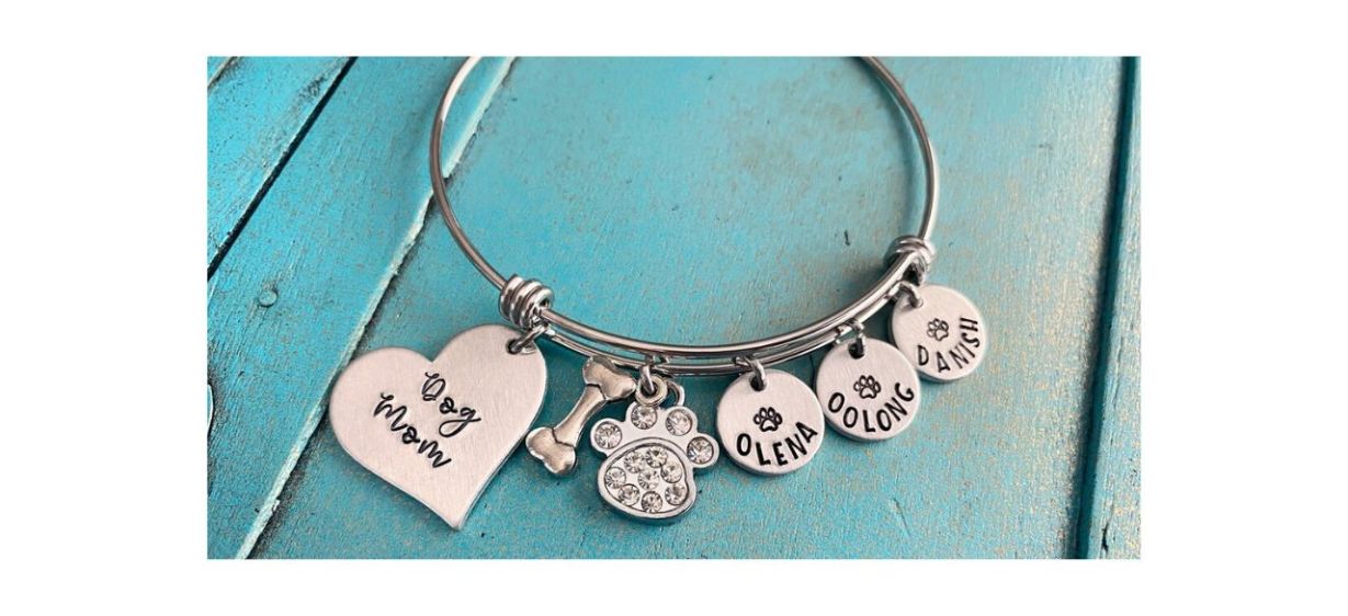 JordanLynnsGems Personalized Dog Mom Bangle Bracelet on blue table; includes charms