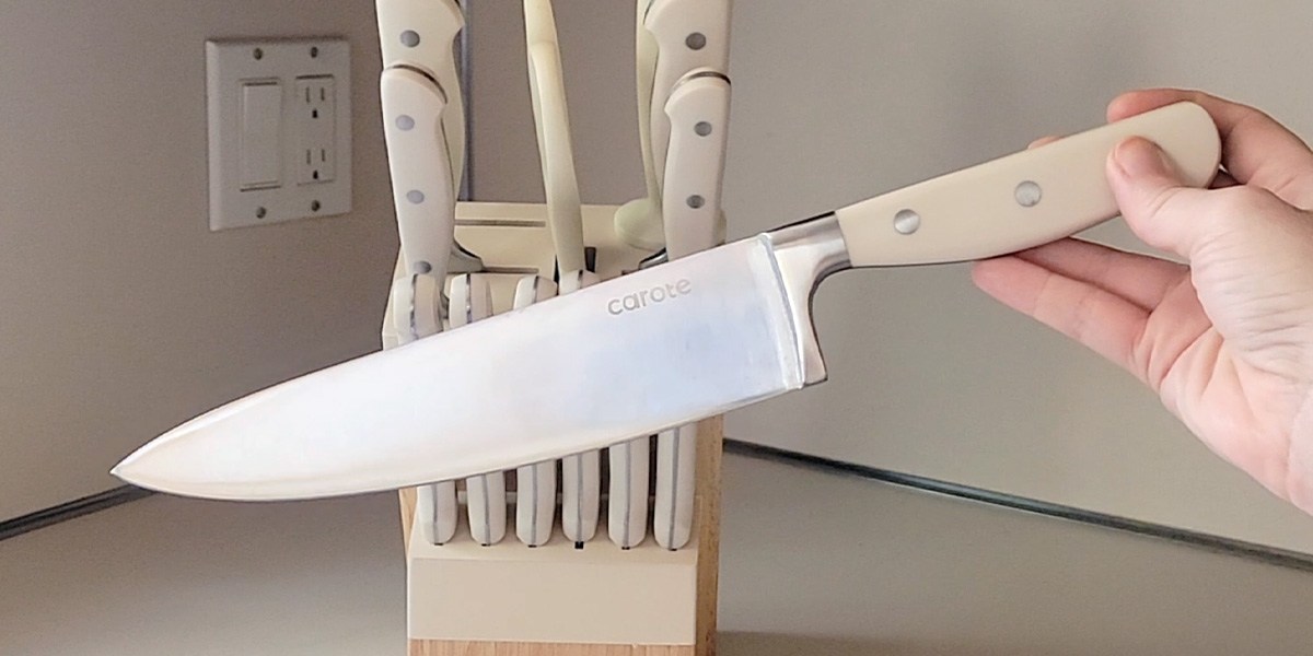 Hand holding knife in front of Carote 14-Piece Forged Knife Set