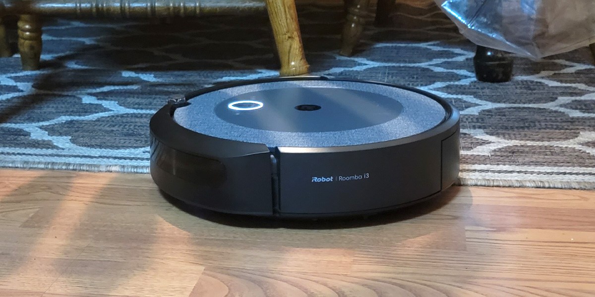 Roomba i3+ EVO cleaning hardwood flooring next to area rug